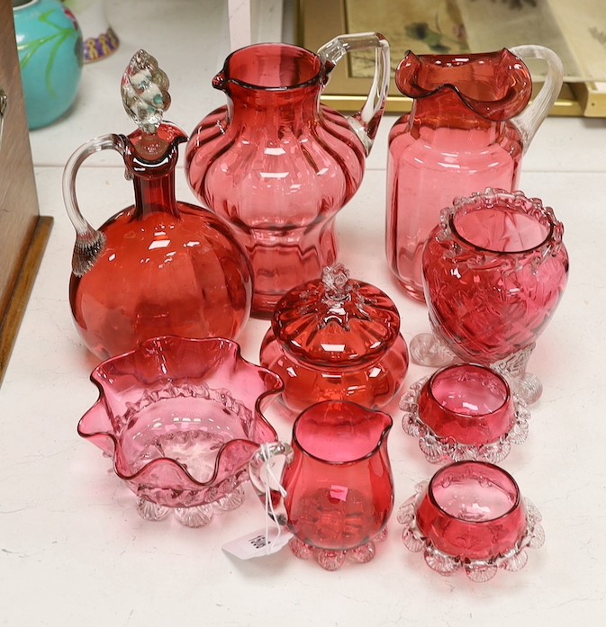 Two tall Victorian cranberry glass jugs, a decanter, a powder bowl ad four other items, tallest item decanter and stopper 27 cms high.